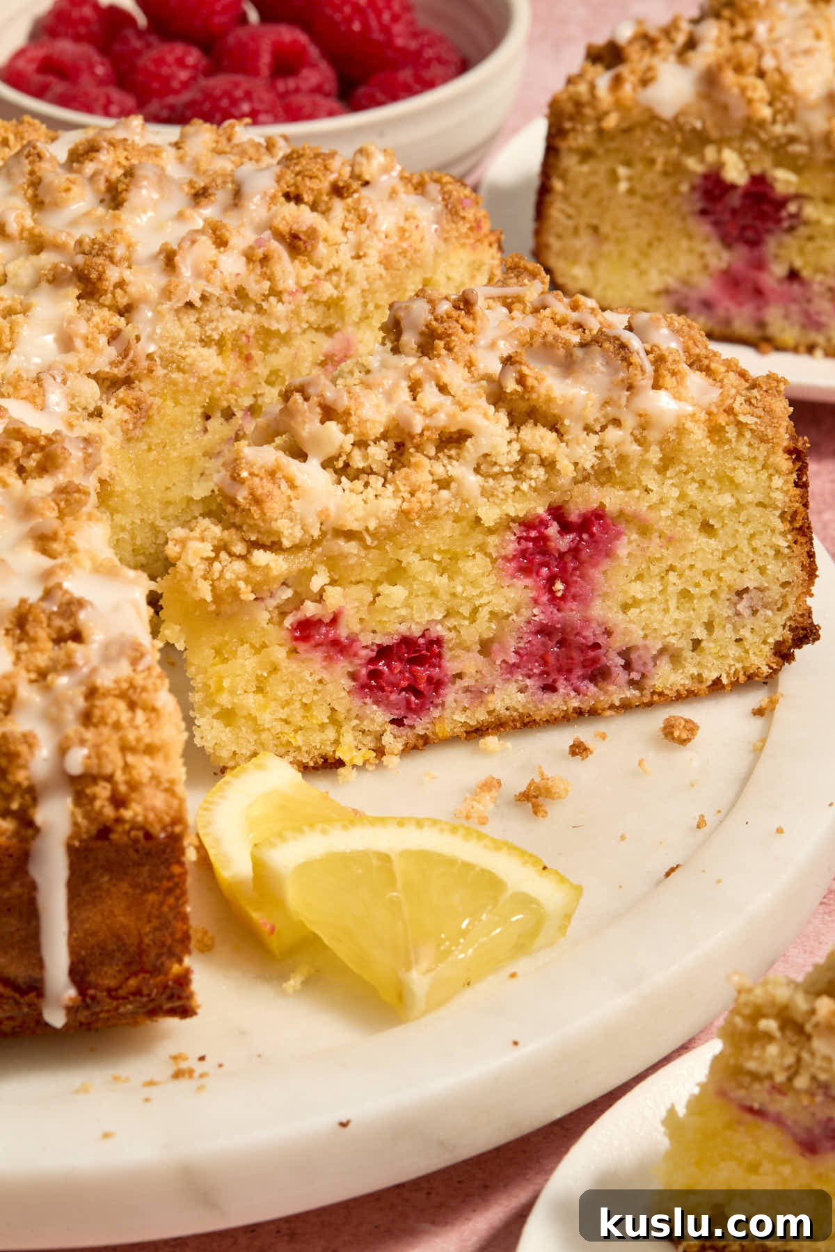 Side view of the cake on a white platter with lemon slices on the side.