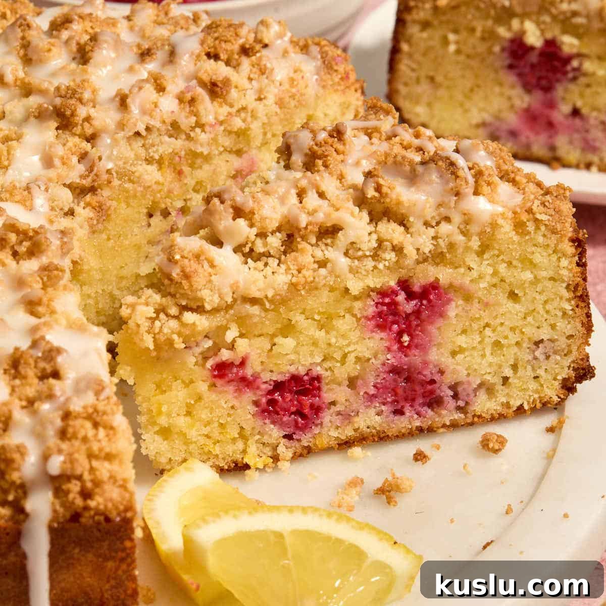 Side view of a slice of almond flour lemon raspberry cake on a white platter.