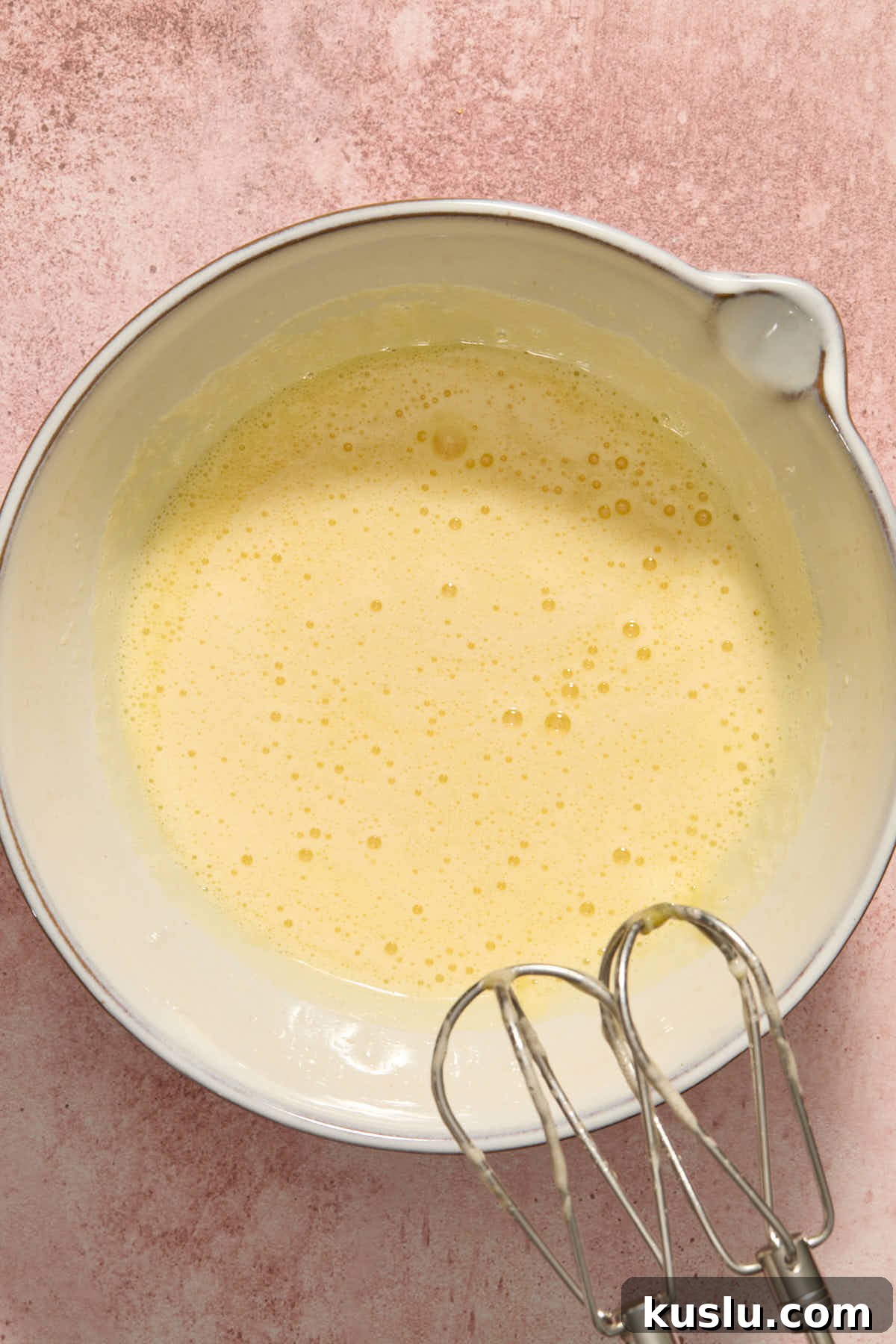 Eggs and sugar beaten together in a large white bowl.