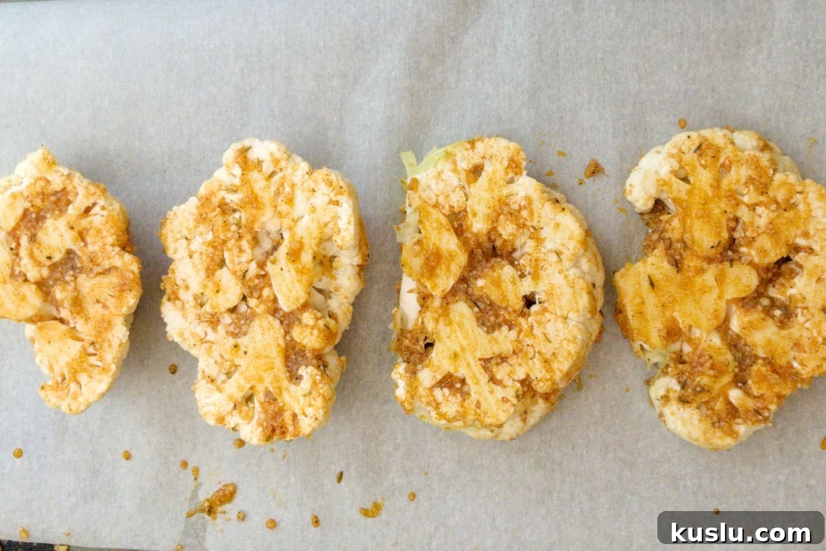 cauliflower steaks brushed with oil and spices and ready to be roasted.