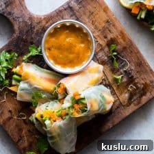 Mango & Bell Pepper Rice Paper Rolls with Mango-Cilantro Dipping Sauce 2 Mango Bell Pepper Rice Paper Rolls with Mango Cilantro Dipping Sauce served on a wooden board.