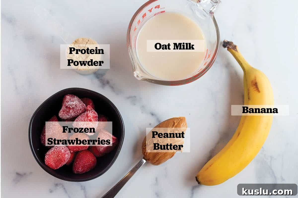 Cup of oat milk, banana, peanut butter, protein powder, and frozen strawberries.