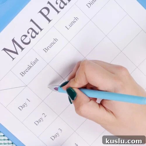 A hand writing filling out a meal plan.