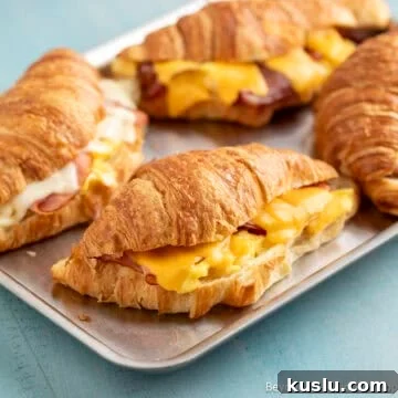 Croissant breakfast sandwiches with ham, bacon, and cheese.
