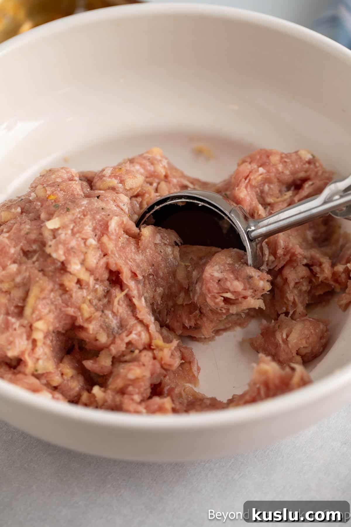 Scooping sausage mixture with a scooper.
