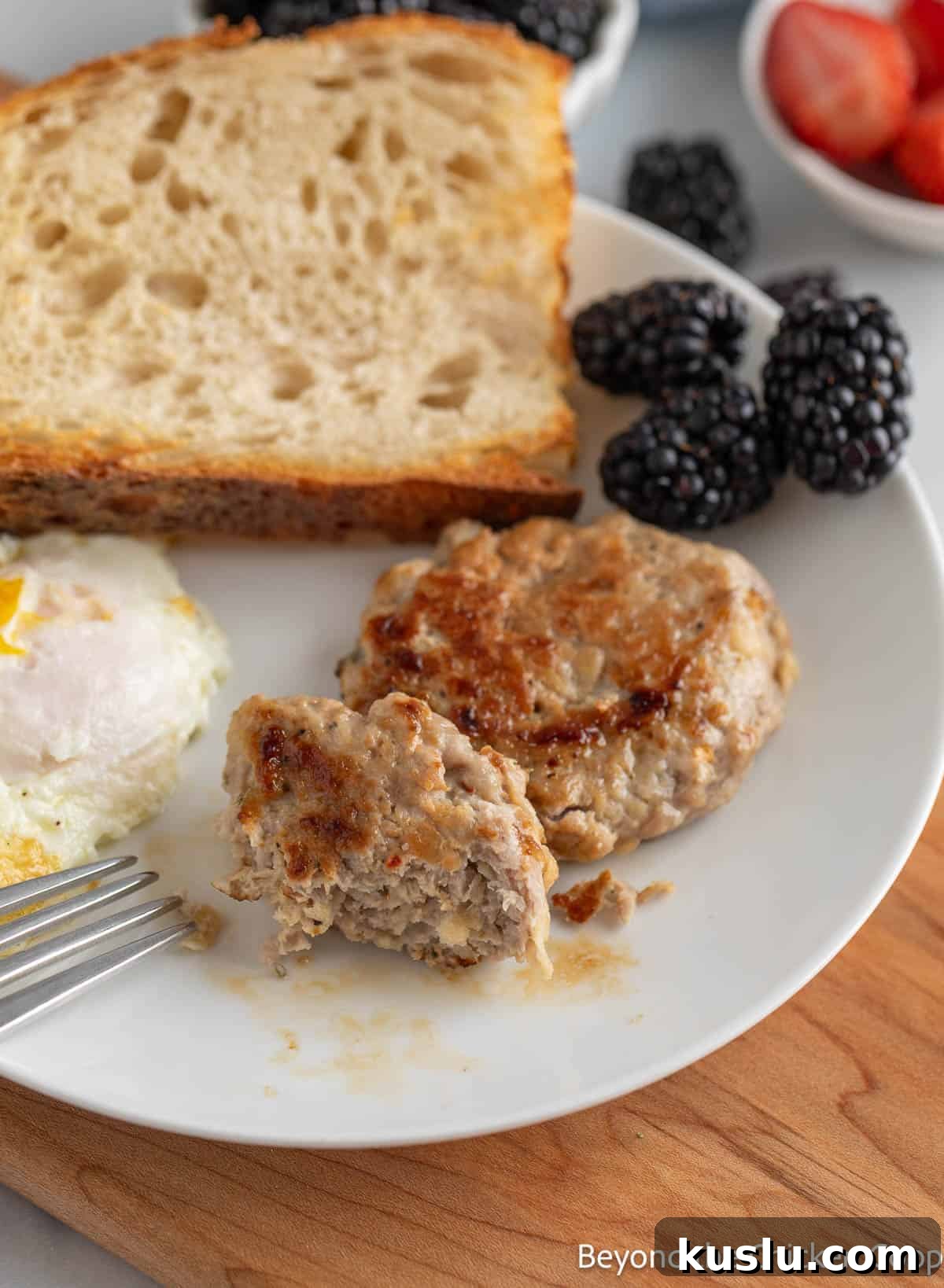 Breakfast sausage on a plate with an egg, toast, and berries.