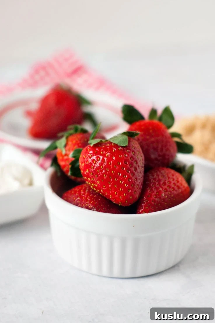 A bowl of strawberries getting ready to dip in sour cream and brown sugar