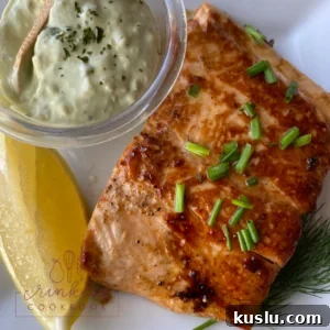 Salmon on a plate with lemon and a dish of tartar sauce