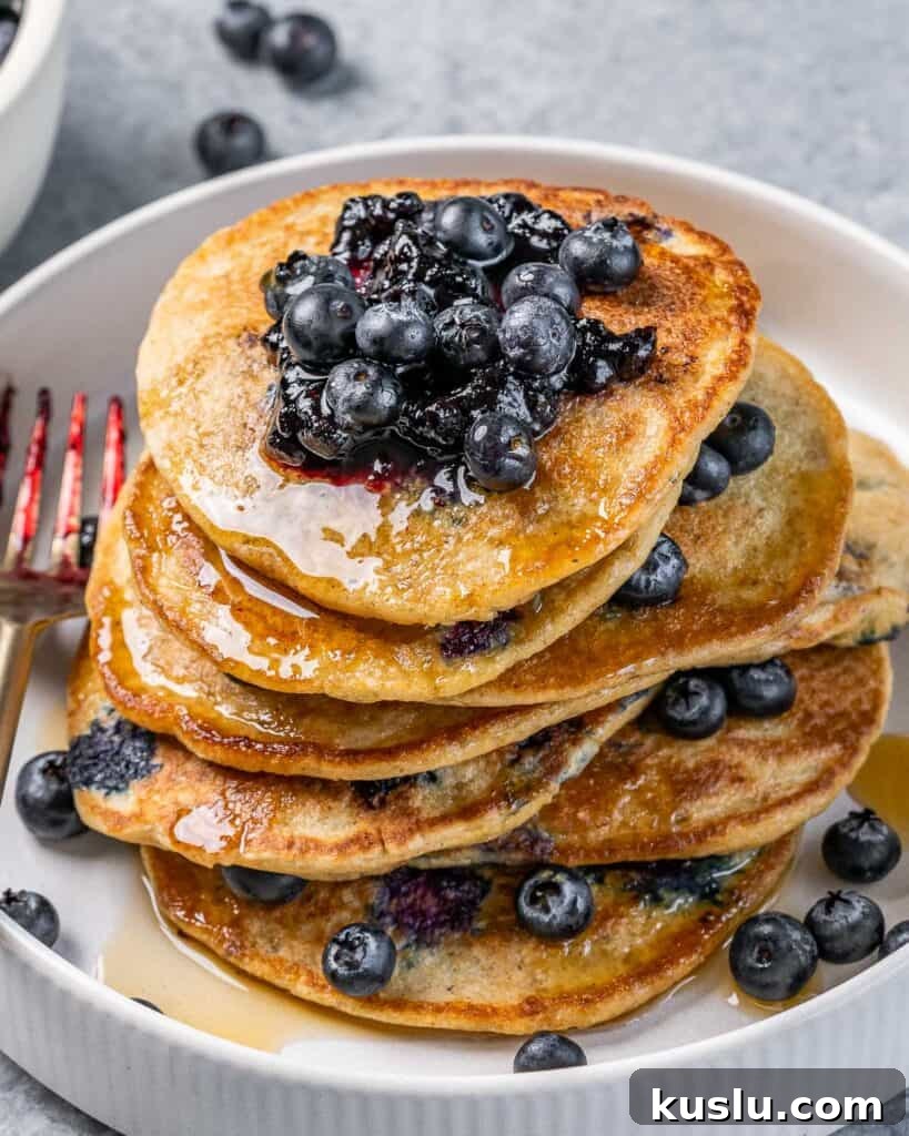 Lemon Blueberry Ricotta Pancakes Recipe for Fluffy, Tangy Stacks 3 Stack of lemon blueberry ricotta pancakes topped with syrup and fresh blueberries.