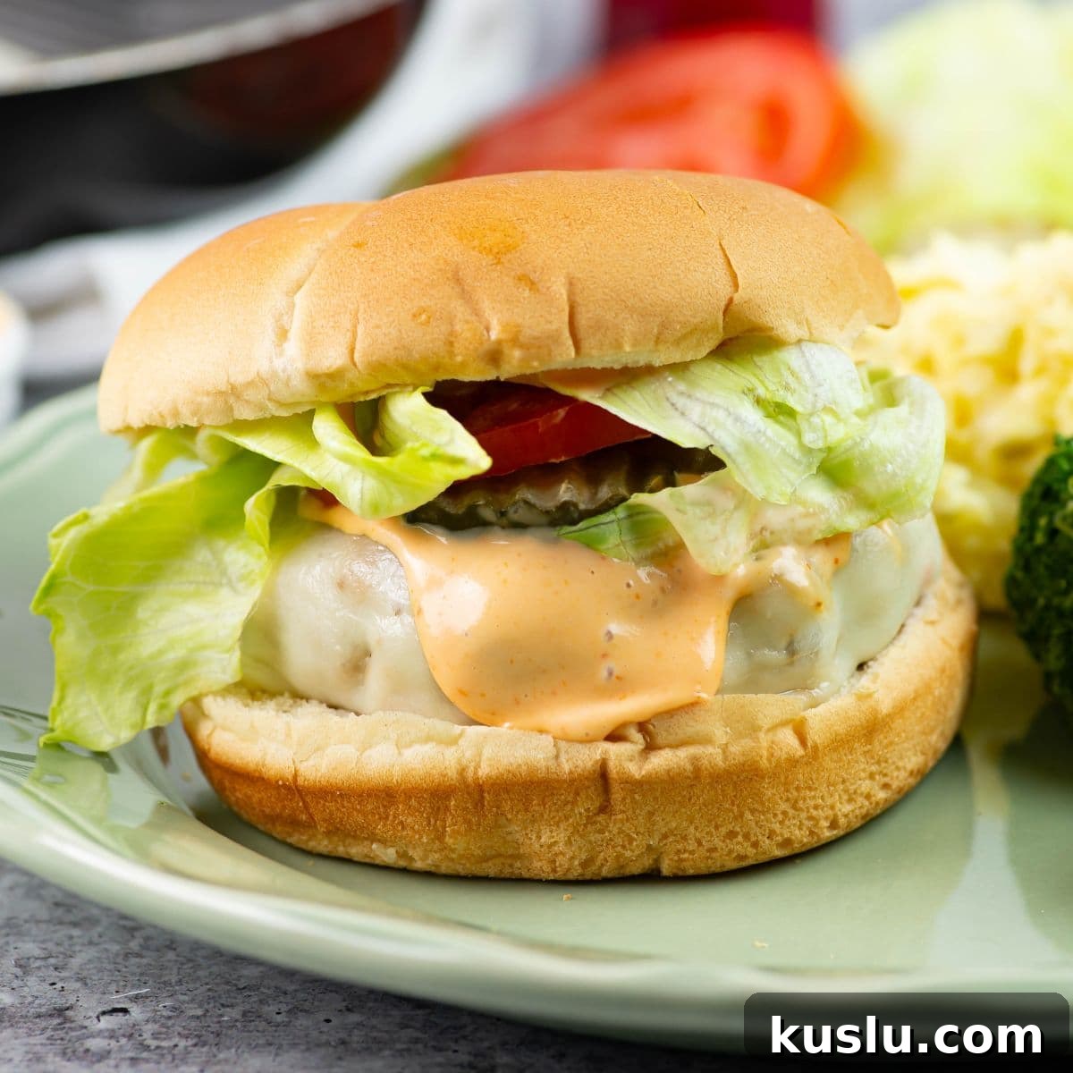 Juicy Grilled Chicken Burgers with Flavorful Toppings 2 Chicken burger on a bun with toppings served on a plate with sides.