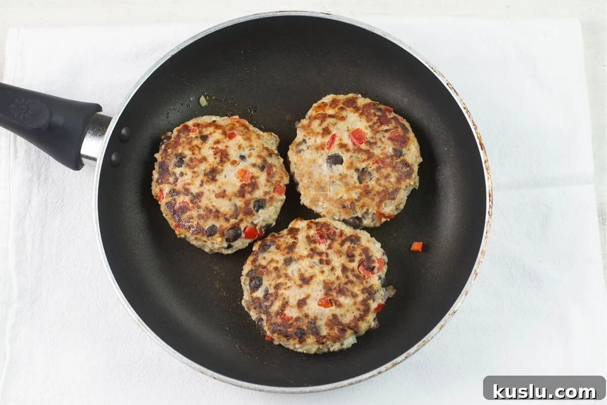 Juicy Grilled Chicken Burgers with Flavorful Toppings 5 3 moist chicken burgers cooked in a skillet.
