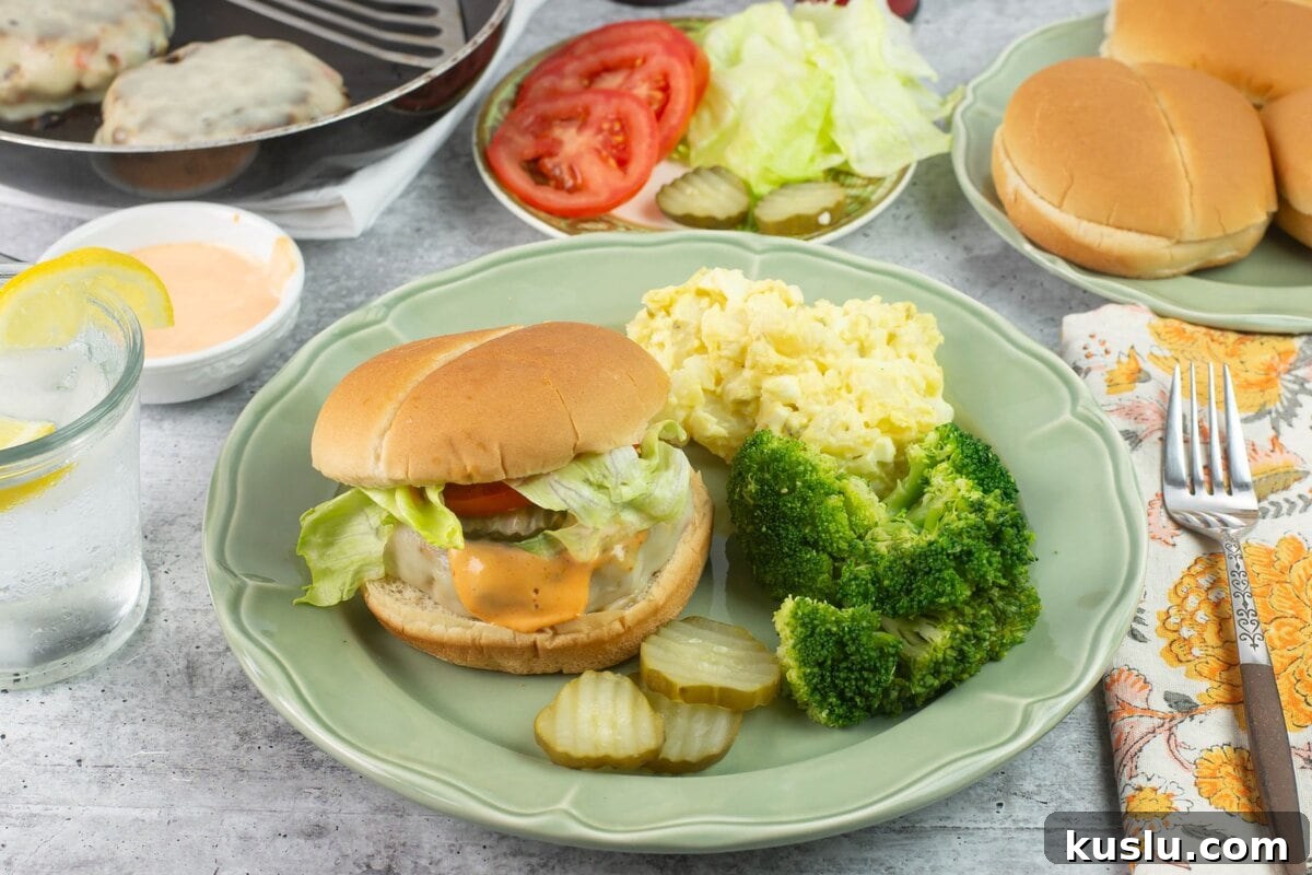 Juicy Grilled Chicken Burgers with Flavorful Toppings 7 Homemade chicken burger meal served with sides and condiments plated on a dinner table.