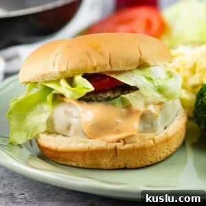 Juicy Grilled Chicken Burgers with Flavorful Toppings 9 Chicken burger on a bun with toppings served on a plate with sides.