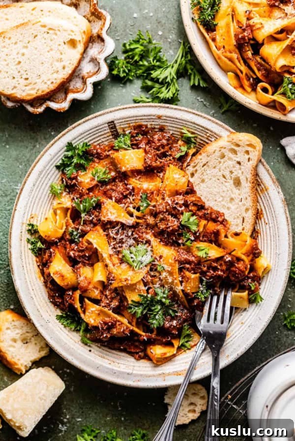 short rib bolognese in a bowl with bread and a fork.