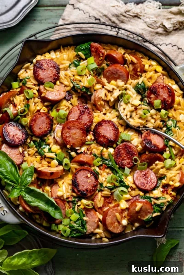 cajun orzo topped with sausage, fresh basil, and diced green onions in a skillet.