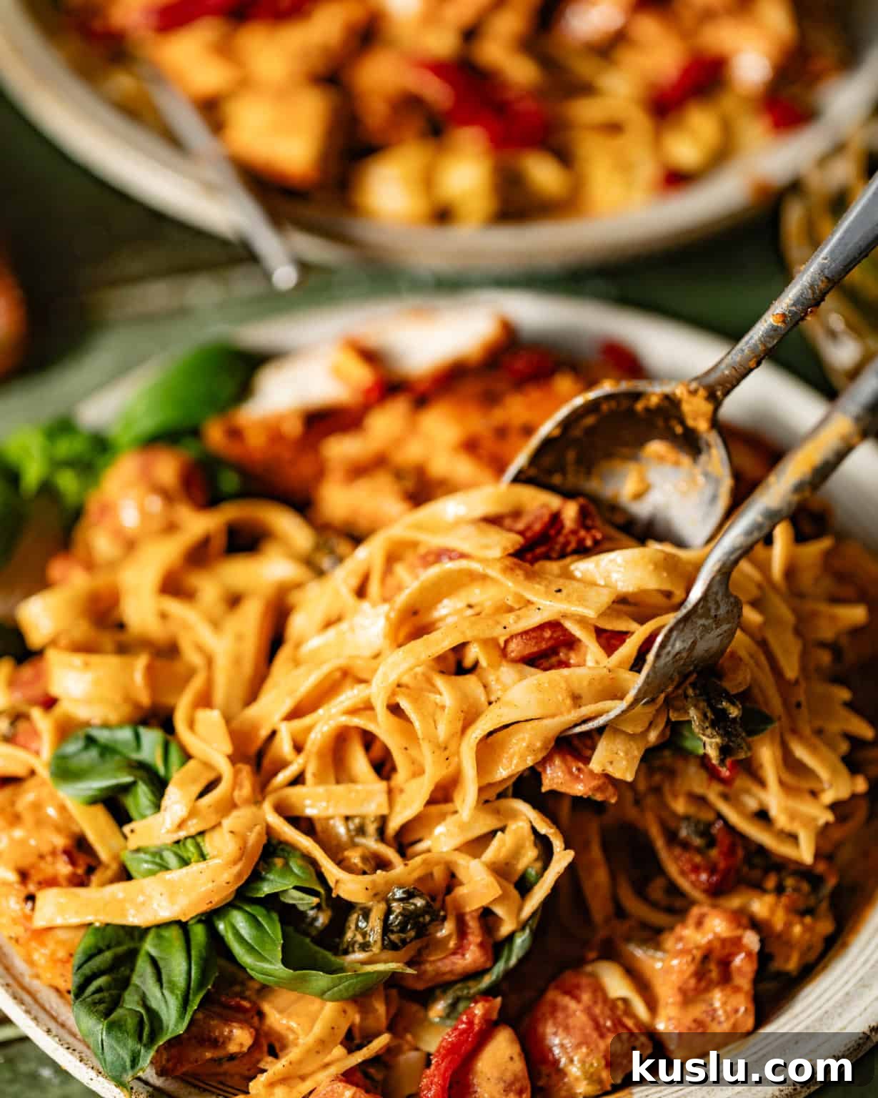 a fork and spoon pulling pasta off of a plate.