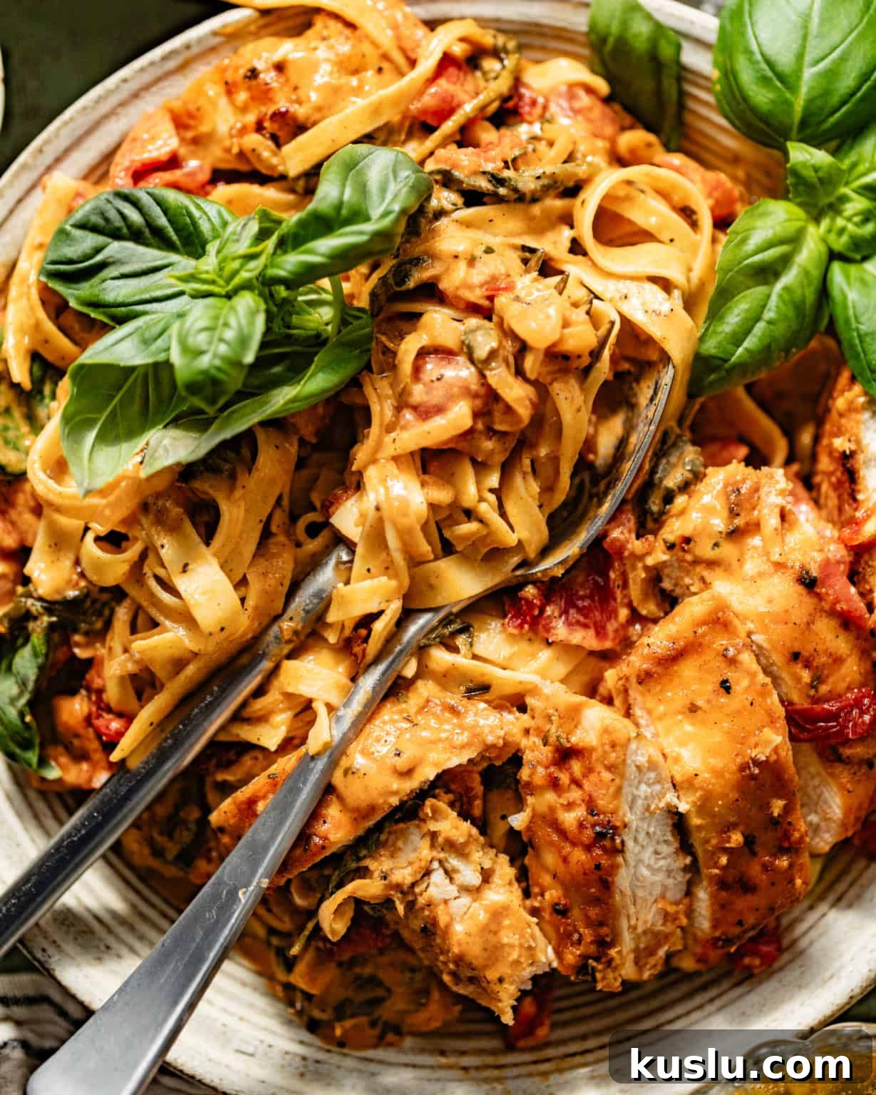 up close photo of marry me chicken pasta with a fork and spoon on a plate.