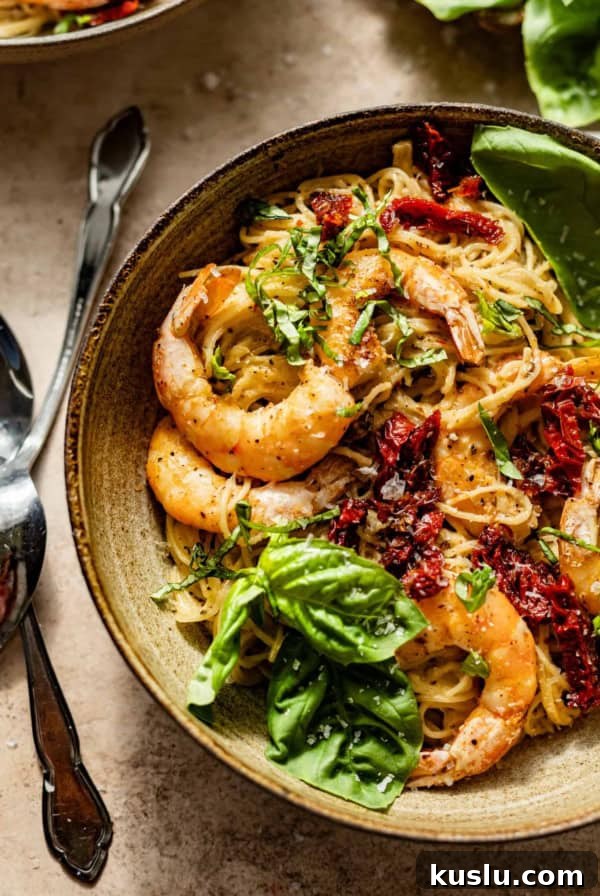 pesto pasta with shrimp in a large bowl with forks and spoons