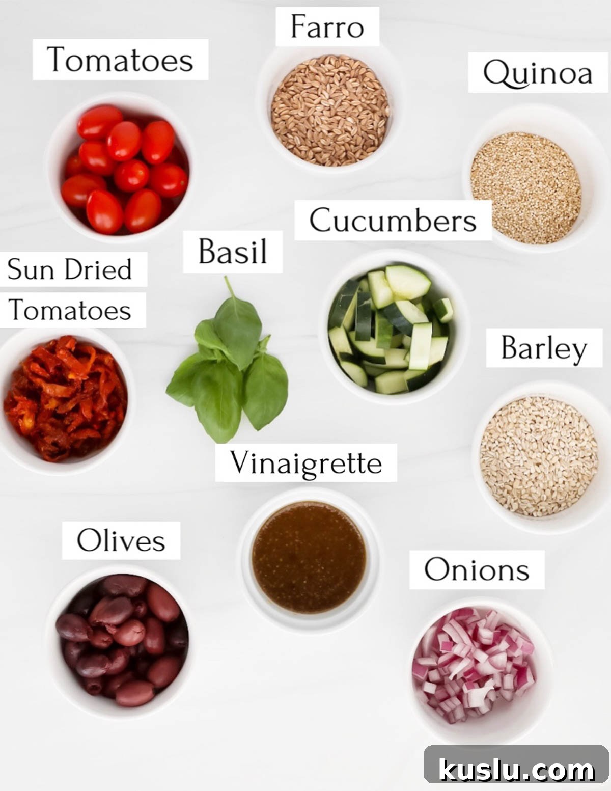 Labeled ingredients in small white bowls including: tomatoes, farro, quinoa, cucumbers, basil, sun dried tomatoes, barley, vinaigrette, olives, onions.
