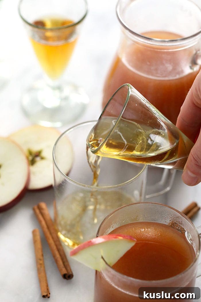 Pouring liquor into cider shot of booze being poured in a mug for spiked apple cider