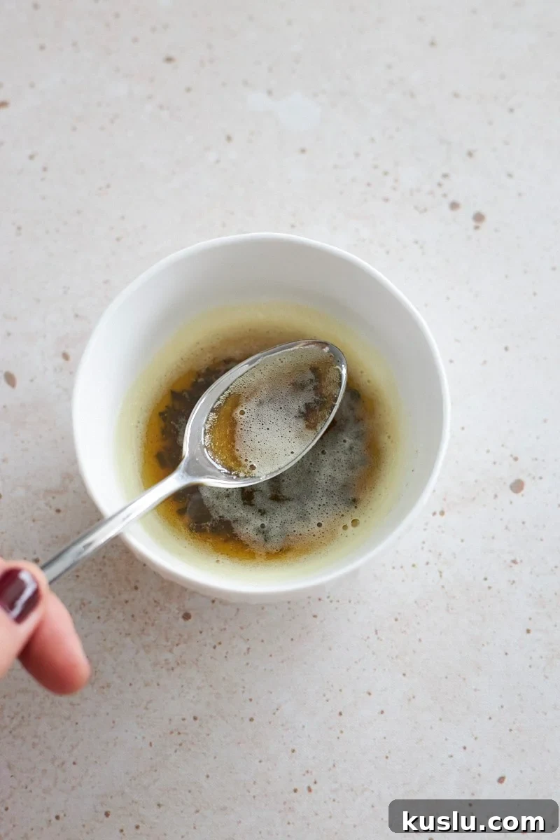 Browned butter mixture with sage in a small white bowl.