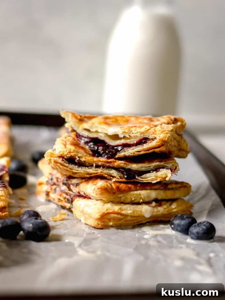 Air Fryer Berry Toaster Strudels: Quick Homemade Breakfast Pastries 3 Air fryer berry toaster strudels stacked on top of a sheet pan.