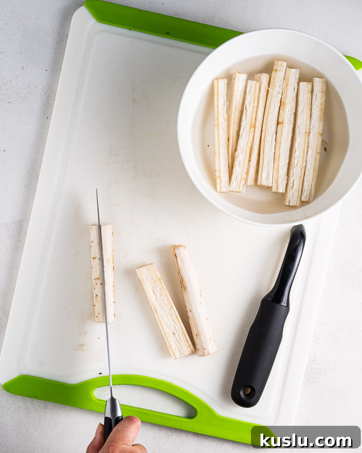 Cutting burdock root into sticks on a cutting board.