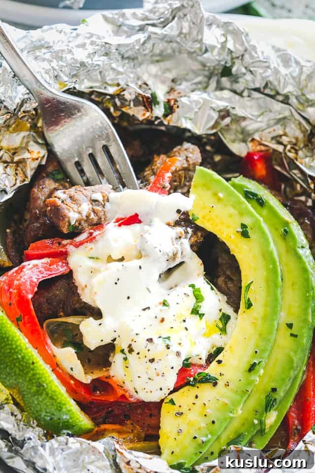 Close-up image of a Foil Pack with Chili Lime Steak Fajitas and a fork taking a bite out of it.