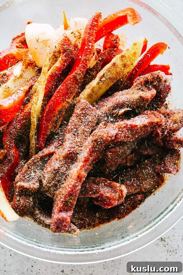 A bowl with sliced flank steak, bell peppers, and onions tossed with fajitas seasoning mix.