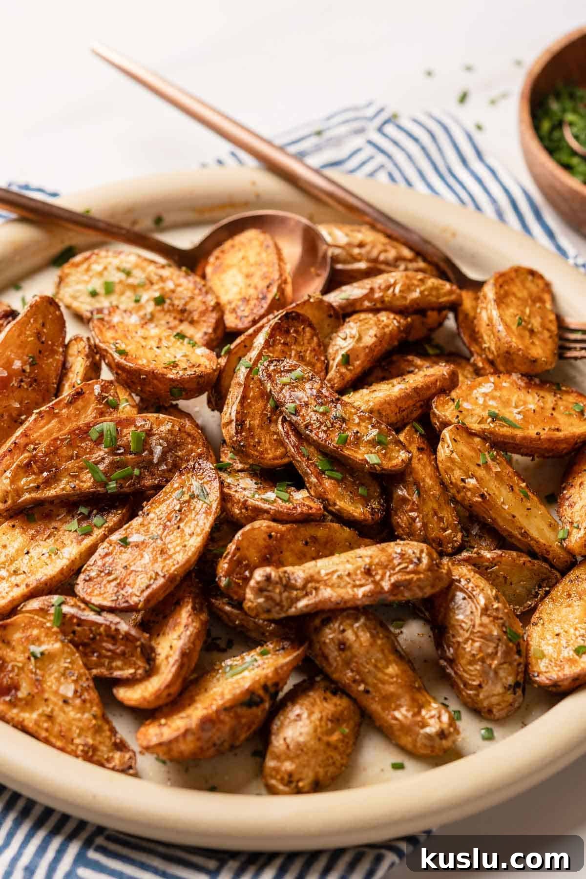 Crispy Air Fryer Fingerling Potatoes Recipe 11 fingerling potatoes on plate with serving utensils on the side