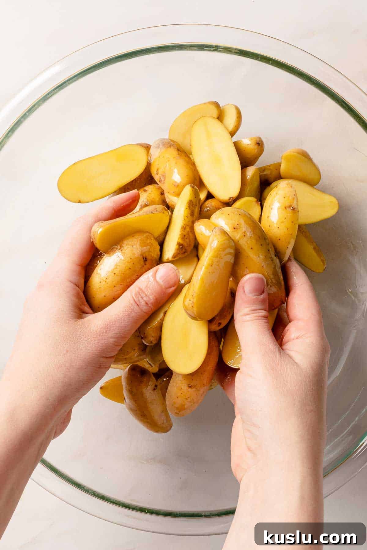 Crispy Air Fryer Fingerling Potatoes Recipe 6 hands tossing cut fingerling potatoes with oil in bowl