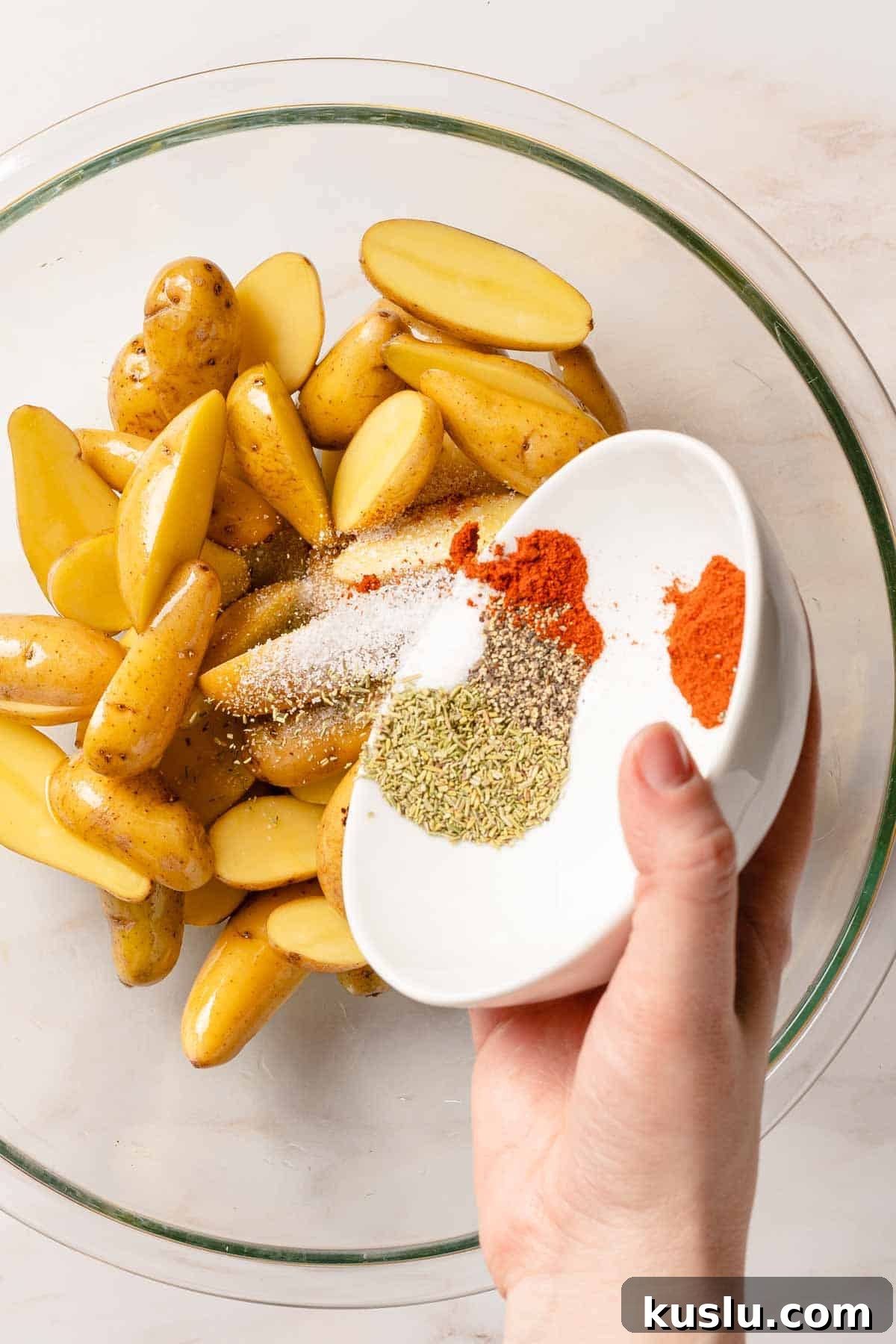 Crispy Air Fryer Fingerling Potatoes Recipe 7 small bowl of seasonings being poured on top of potatoes in bowl