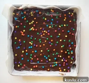 add the chocolate ganache and top with coloured chocolate chips to finish the homemade cosmic brownies 