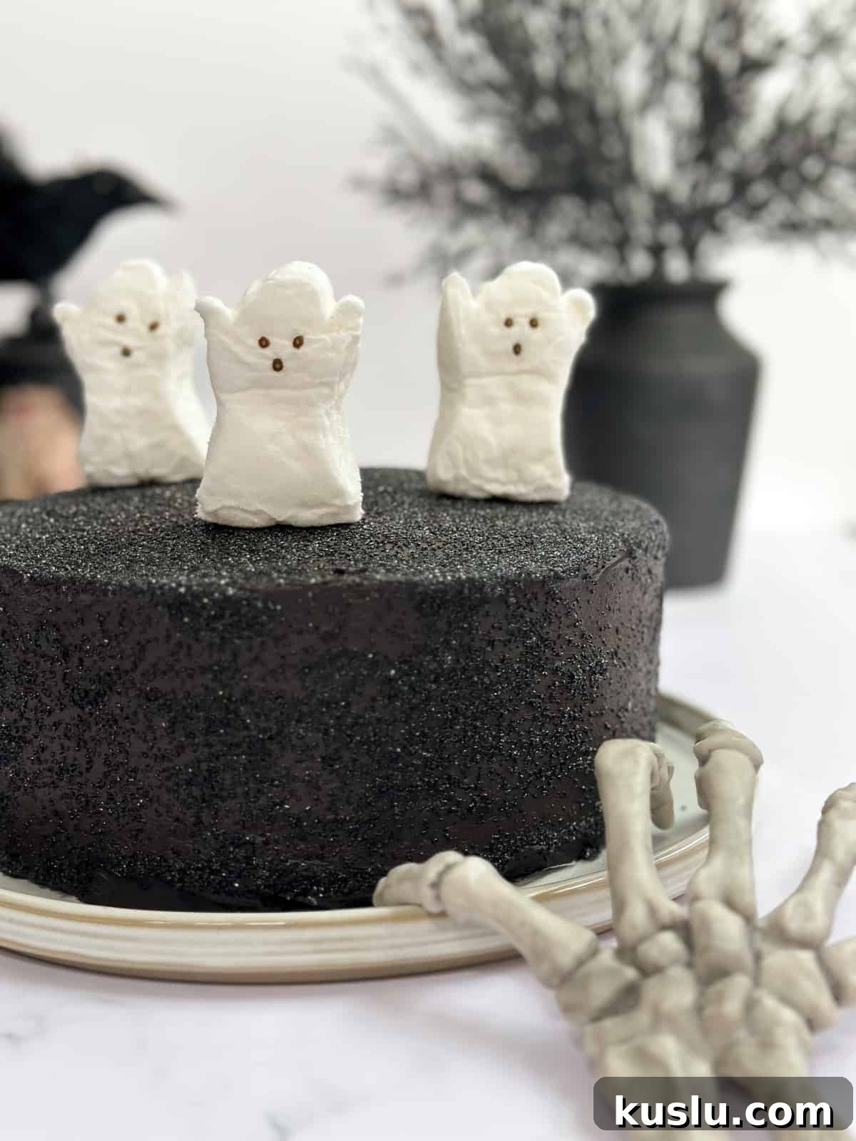 a view of the whole black chocolate cake with ghosts on top.
