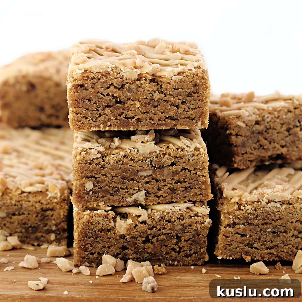 Biscoff Blondie Bars: Chewy Lotus Biscoff Cookie Dessert 6 A stack of three cookie butter bars showing the dense, chewy texture dotted with crunchy bits of toffee.