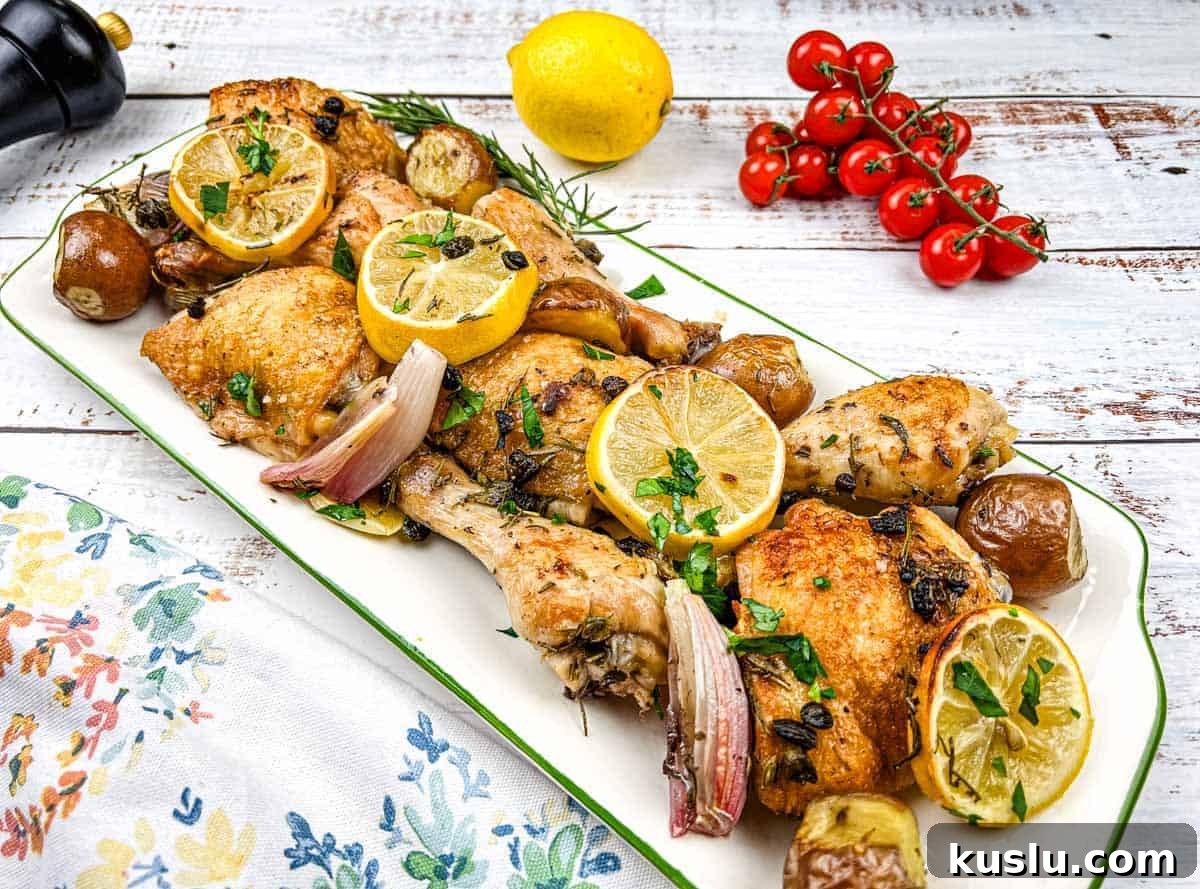 17 Tangy Lemon Recipes Made for Flavor, Not Fancy Presentation 16 A platter of sheet pan lemon-rosemary chicken with lemon slices, herbs, and garnished with cherry tomatoes.