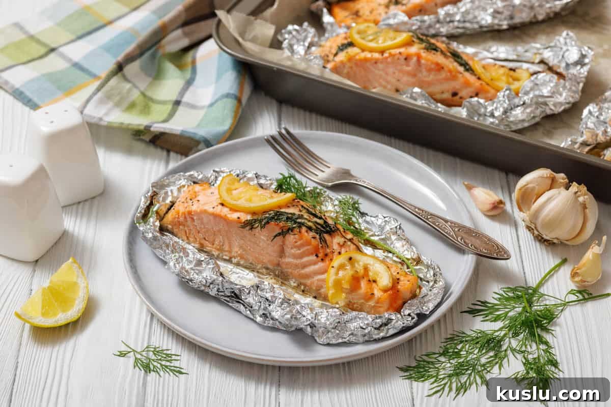 17 Tangy Lemon Recipes Made for Flavor, Not Fancy Presentation 19 A close-up, slightly high-angle shot of a single Lemon Dill Salmon Foil Packets , seasoned with lemon and dill, still nestled in its aluminum foil packet on a light gray plate, with a silver fork to its right.