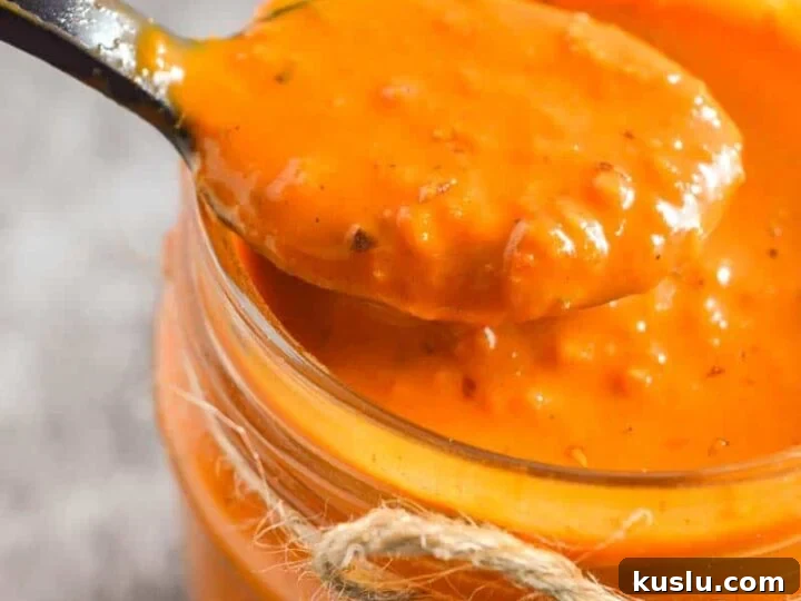 Closeup of a black spoon with slightly chunky orange sauce
