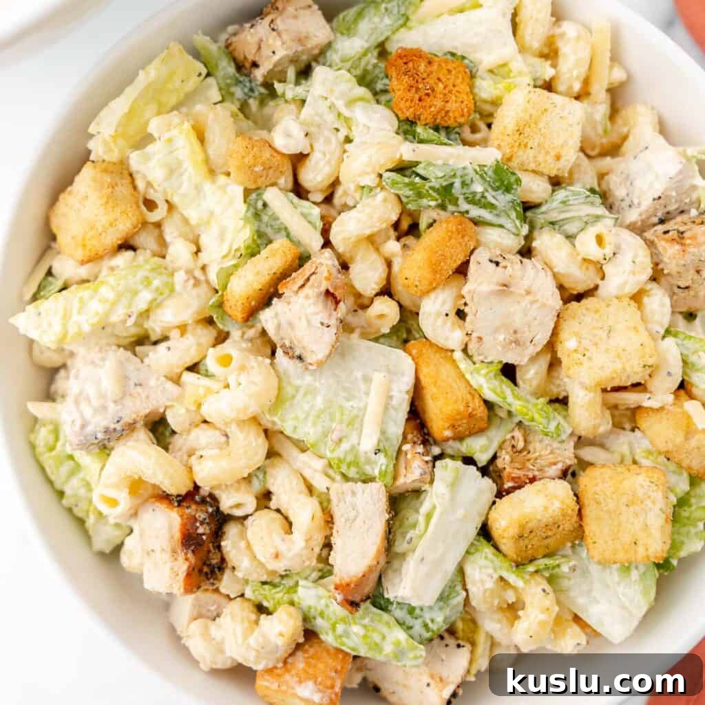 Mediterranean Tuna Pasta Salad with Olives and Cherry Tomatoes 9 A bowl of Caesar salad with grilled chicken pieces, croutons, lettuce, and pasta, mixed with creamy dressing.