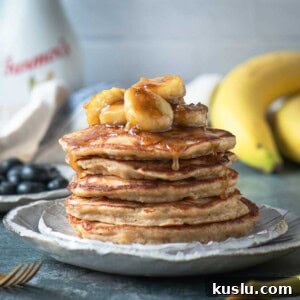A close up of a stack of pancakes with banana compote on top.