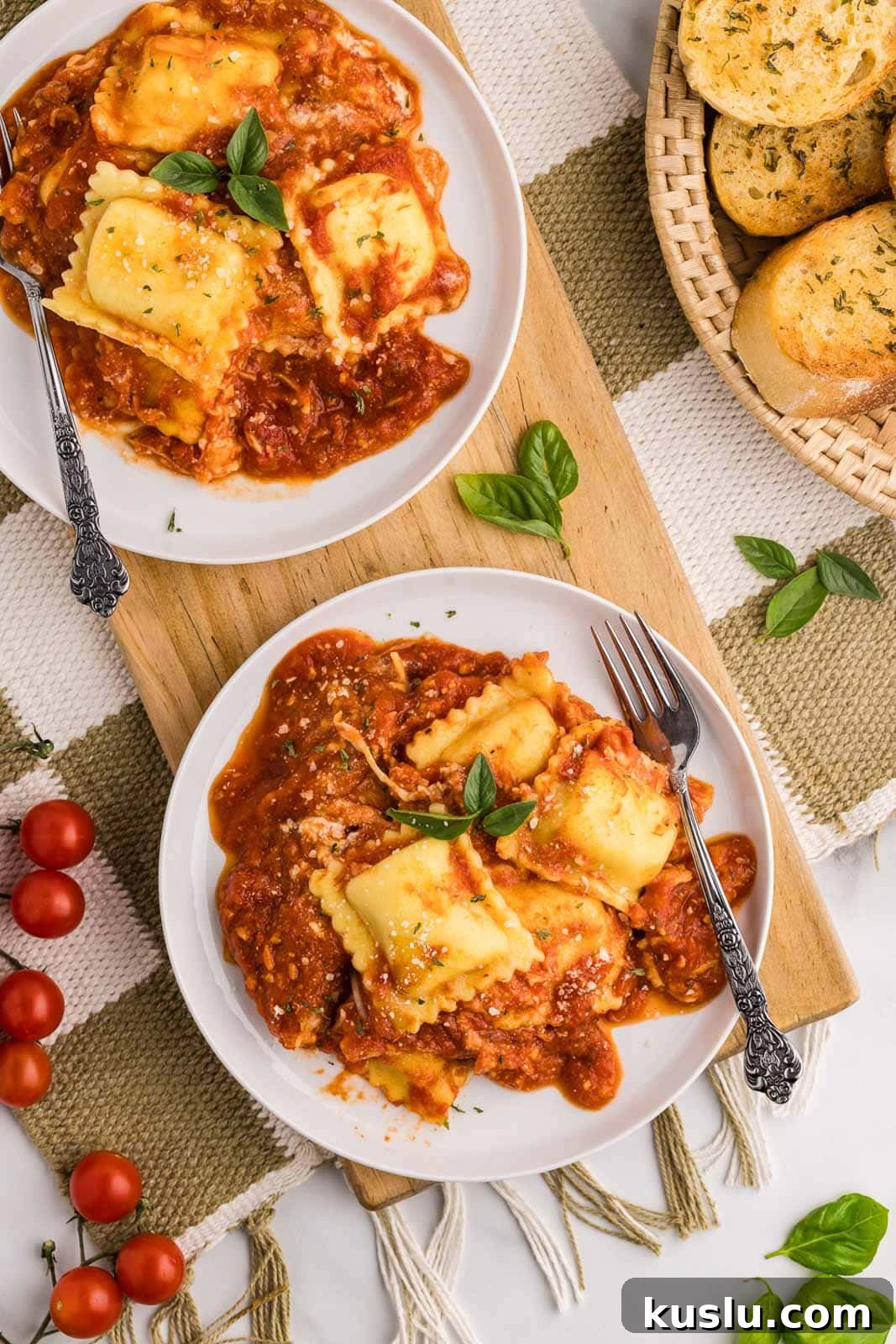 Slow Cooker Ravioli Lasagna: Comforting One-Pot Dinner 6 overhead view of two plates of ravioli lasagna, each on wooden cutting board with a fork, with basket of garlic bread on side