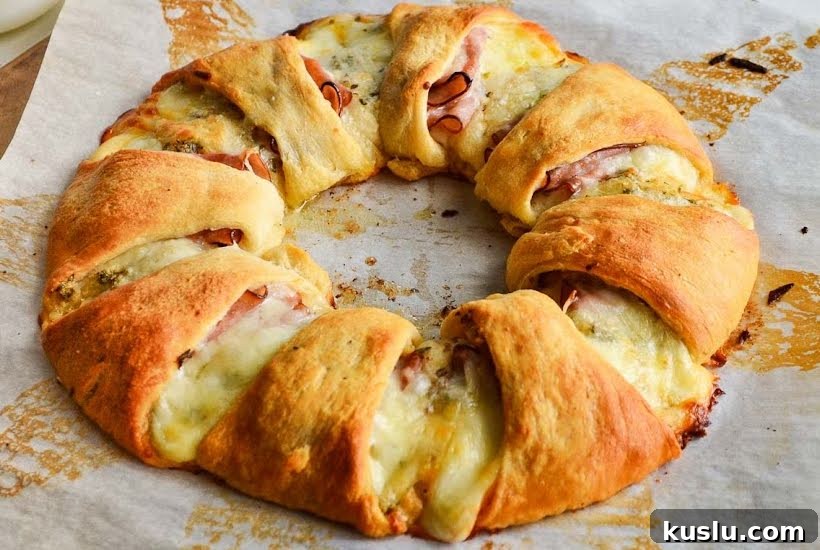 Baked Pillsbury crescent ham and cheese ring on parchment paper.