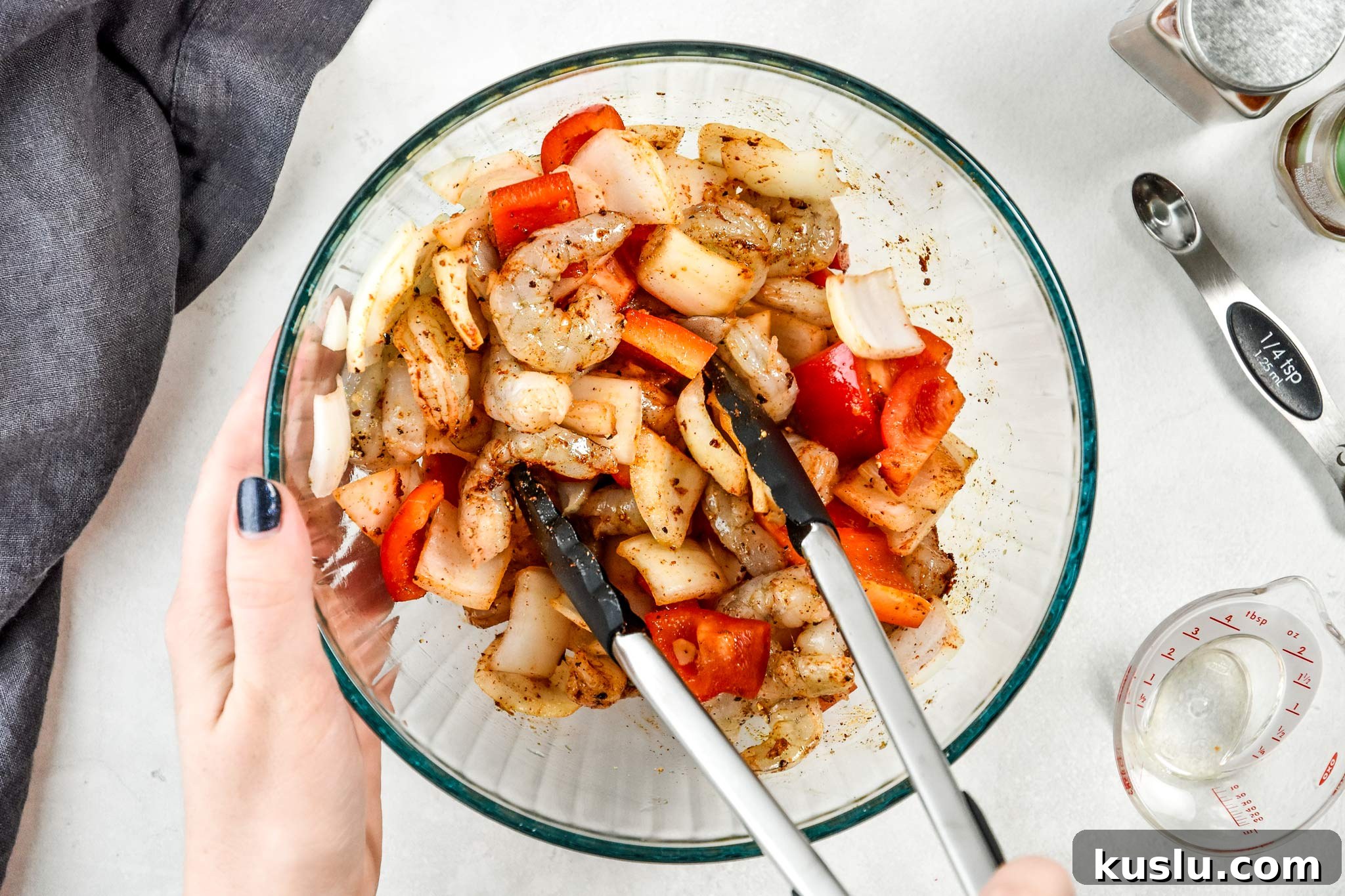 Crispy Air Fryer Shrimp with Roasted Vegetables 4 using tongs to stir the spices, shrimp and veggies in a bowl