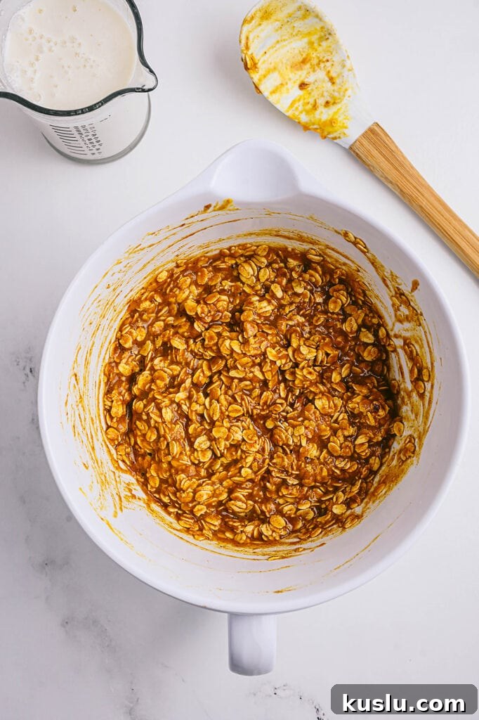 Overhead image: pumpkin oatmeal batter in a white bowl with a spatula off to the side.