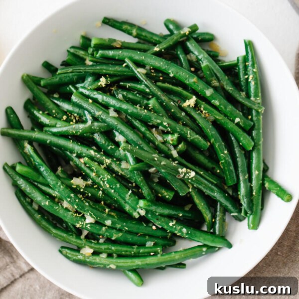 Green beans topped with lemon in a white bowl.