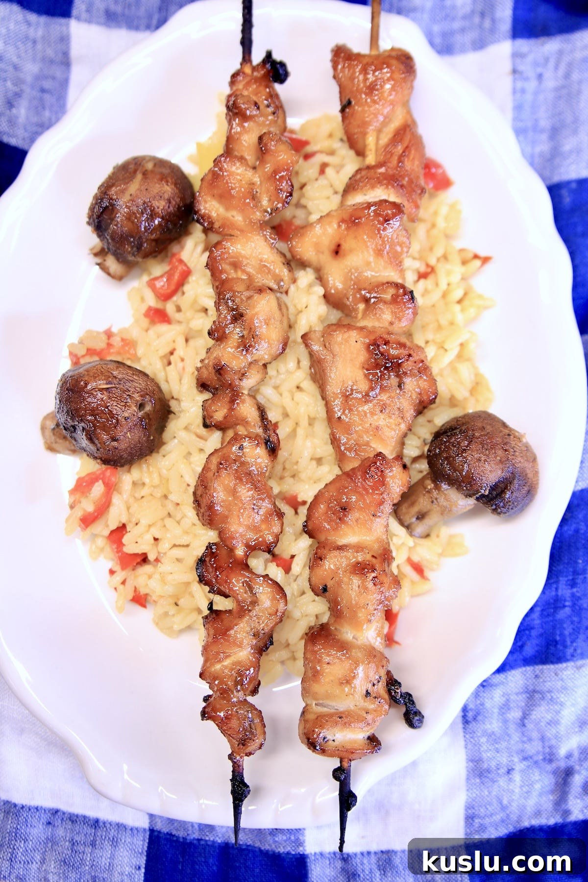 Plate of rice, chicken skewers and mushrooms.