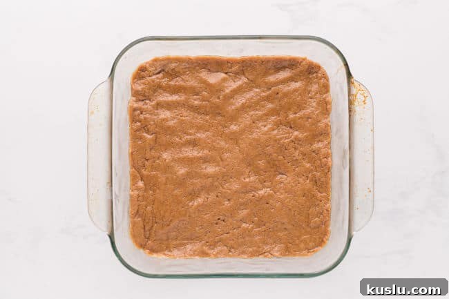 Chewy Peanut Butter Cookie Bars Recipe for Crowd-Pleasing Treats 6 Cookie dough pressed into a baking dish.