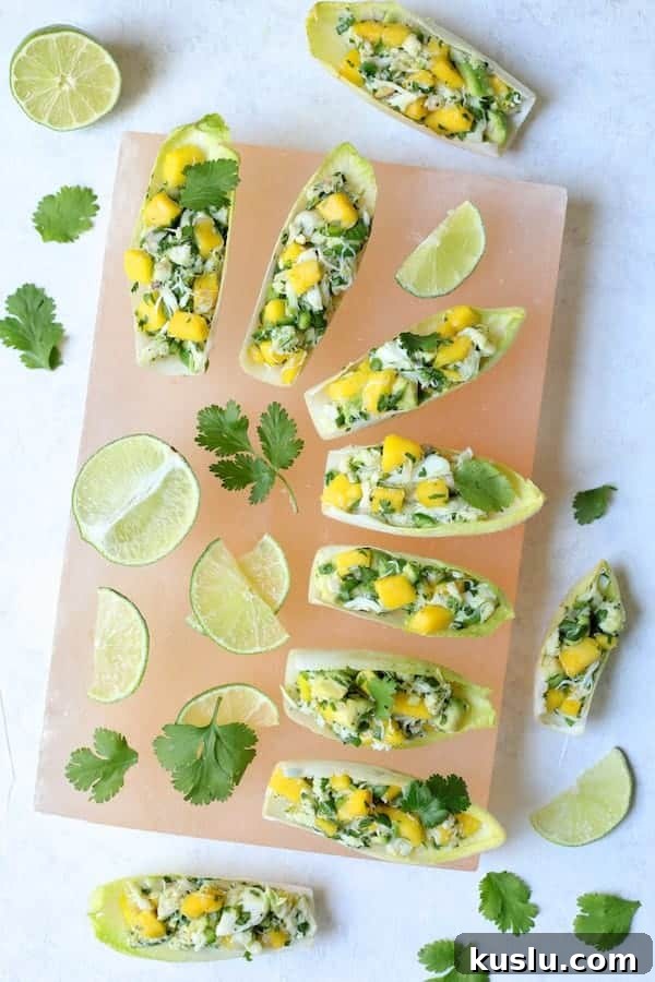 Photo of Crab Mango and Avocado Salad with Chile Lime Dressing in Endive on pink salt block.