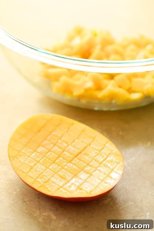Photo showing how to easily dice a mango with some in glass bowl already diced.