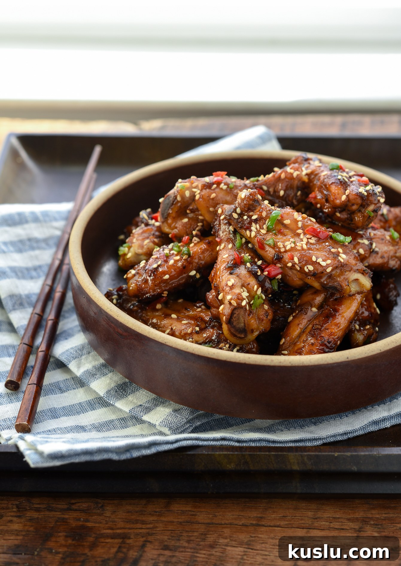 Korean honey garlic chicken wings with fresh chili garnish in a serving bowl